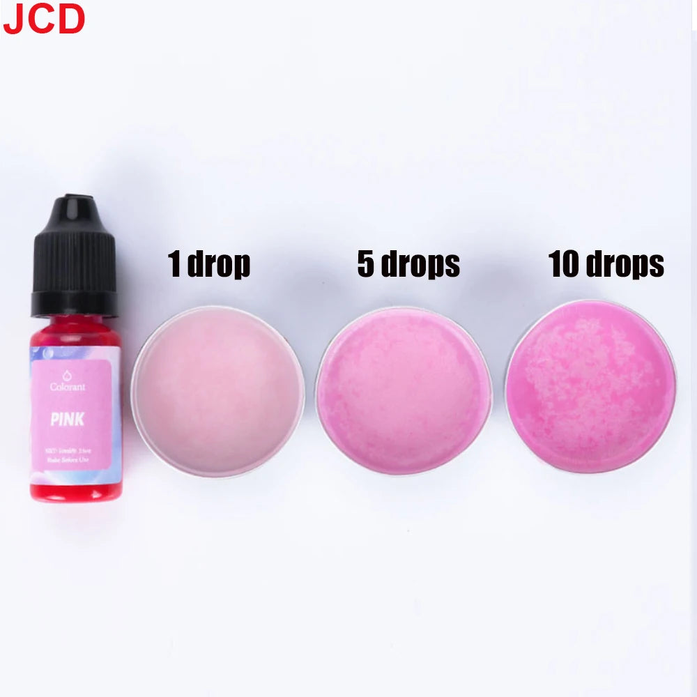 A bottle of pink liquid candle dye with dropper, next to three petri dishes showing 1, 5, and 10 drops of the pink color.