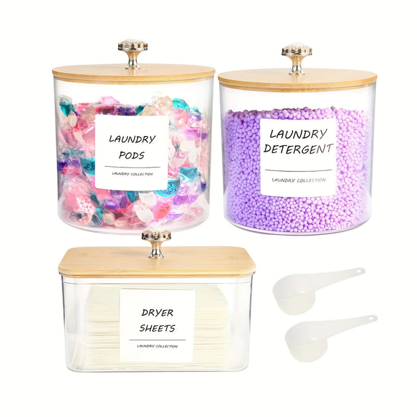 Three glass containers hold laundry detergent pods and dryer sheets with wooden lids.
