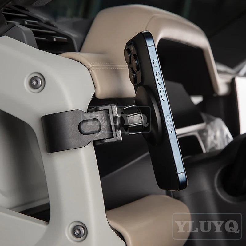A black magnetic car phone mount is shown attached to a light beige interior panel of a vehicle.