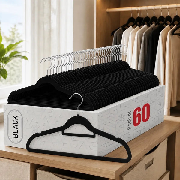 A set of black velvet hangers with chrome hooks is displayed on a wooden shelf.