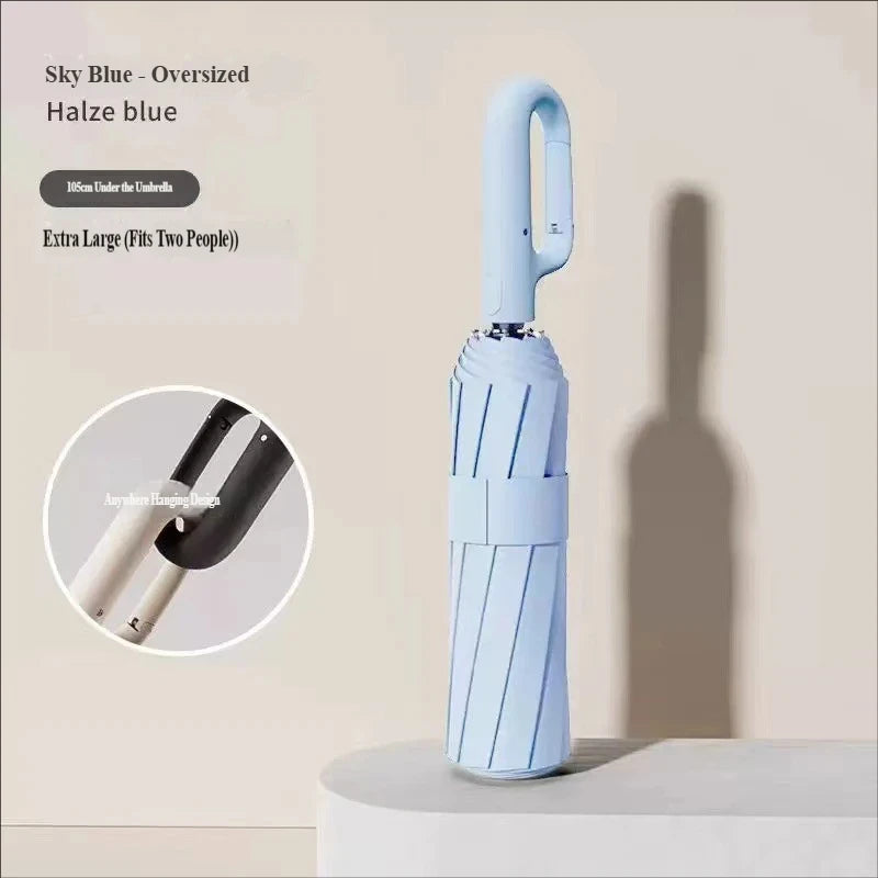A light blue automatic folding umbrella is shown standing upright on a white surface.