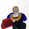 A velvet cowboy hat jewelry storage box with a gold-colored felt hat and blue velvet fabric.