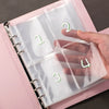 A pink budget challenge binder with clear plastic sleeves showing numbered cash envelopes.