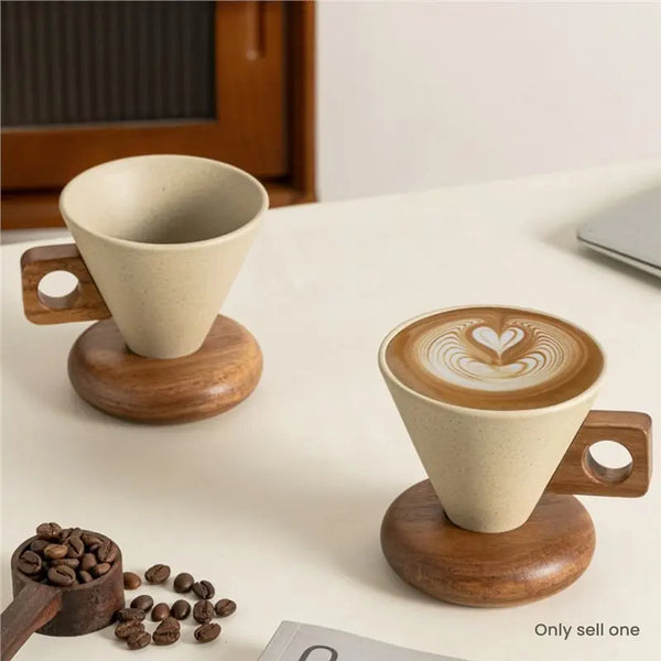 A ceramic coffee mug with a wooden base and spoon set sitting on a white surface.