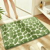 A rectangular green pebble embossed bathroom rug placed on a wooden floor.