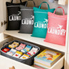 A collection of black, gray, teal, and pink fabric laundry bags hanging in a closet, with a storage box of folded items below