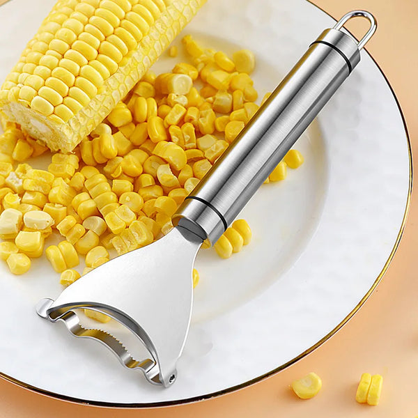 A stainless steel corn stripper tool is shown next to corn kernels on a white plate.