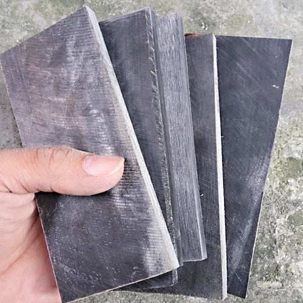 Two pieces of dark gray natural buffalo horn knife handles are shown being held and displayed.