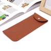 A brown PU leather eyewear case or glasses bag resting on a white surface next to an open magazine.
