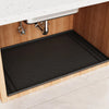A dark silicone mat is placed inside a kitchen cabinet under the sink.
