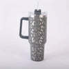 A mottled gray leopard print insulated stainless steel tumbler with a handle and straw.