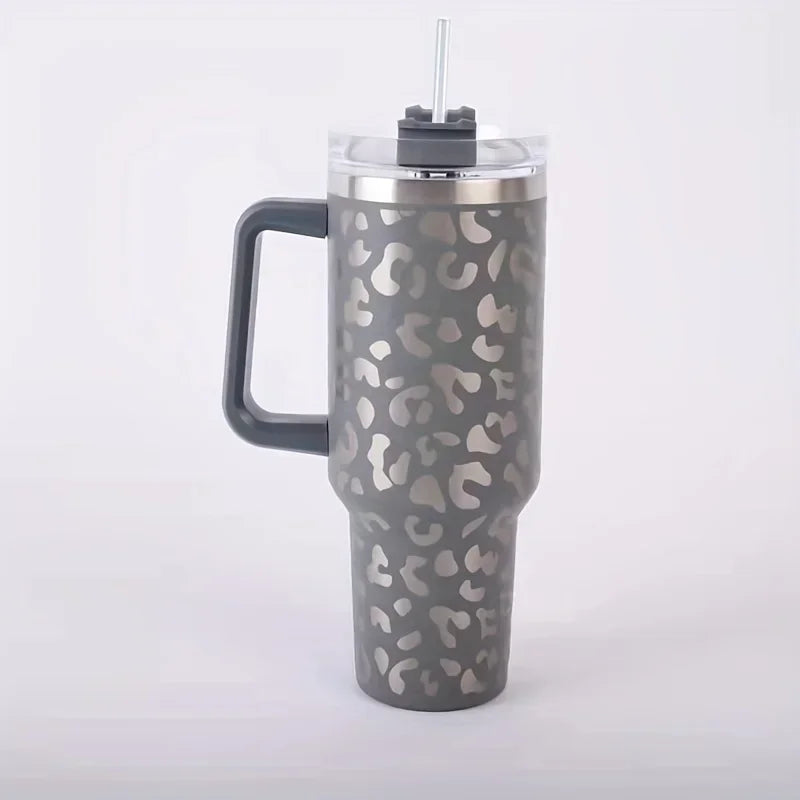 A mottled gray leopard print insulated stainless steel tumbler with a handle and straw.