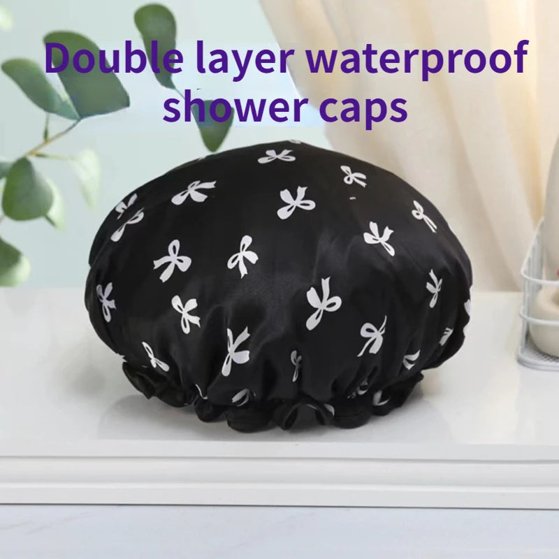 A black reusable double layer waterproof shower cap with white floral patterns resting on a white surface.