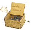 A wooden music box with an engraved lid that reads Can't Help Falling in Love and a small metal mechanism inside.