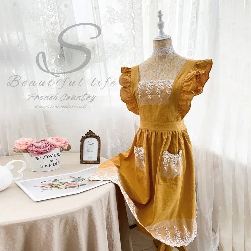 Gelbes Leinen-Baumwoll-Schürzenkleid mit Spitzendetails auf einem Mannequin.