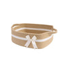 A woven cotton rope storage basket in beige with white stripes and a white bow.
