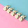 A row of light beige plastic clothes hanger hooks arranged diagonally on a pink and blue background.
