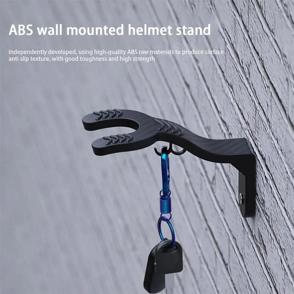 A black ABS wall mounted helmet stand hook is shown hanging on a gray wooden surface.