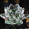 A clear crystal lotus flower tabletop decor with green accents, reflecting light on a dark surface.