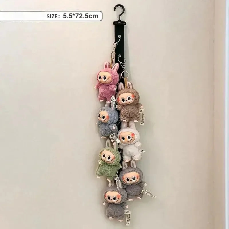 A vertical display rack featuring multiple small, fuzzy Labubu-style plush figures hanging on a black hook.
