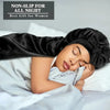 A woman is sleeping with a black satin sleeping bonnet on her head, resting on white bedding.