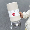 A hand holds a large white stainless steel insulated tumbler with a lid and straw, featuring a NEW Sports label.
