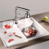 Un extensor de grifo de cocina dispensando agua sobre un tazón de fresas frescas en una instalación de fregadero moderna.