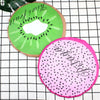 A reusable fruit shower cap shaped like a kiwi slice, pink, and green, placed on a black and white grid.
