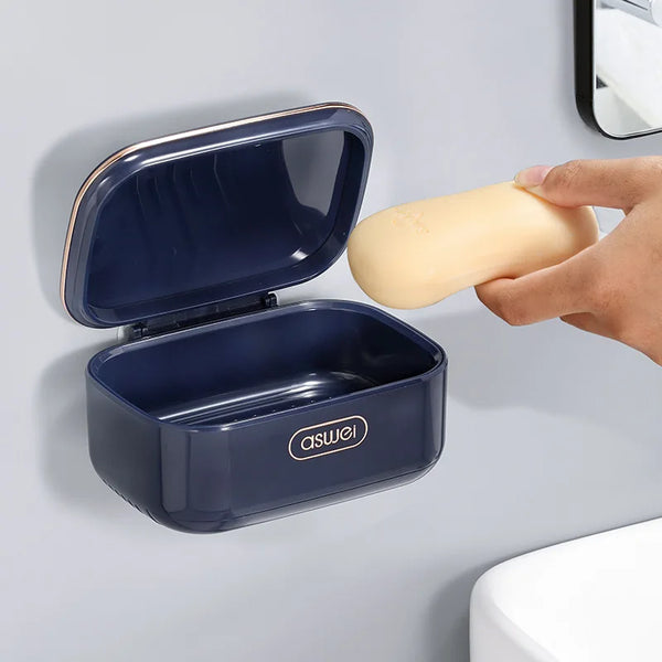 A dark blue double-layer drain soap holder rack with an open lid and a yellow soap bar is shown against a gray wall.