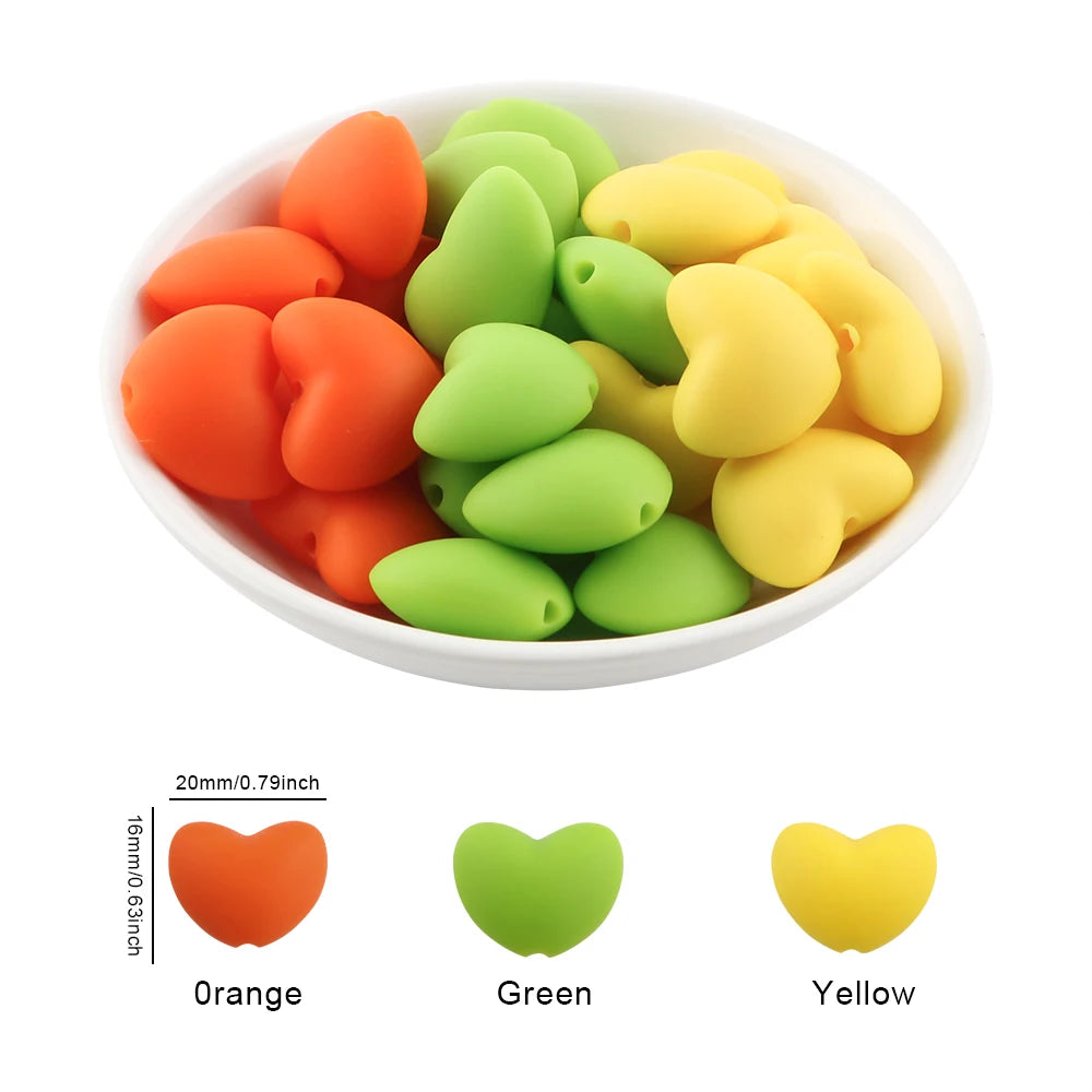 A bowl filled with ten silicone charm beads in orange, green, and yellow colors.