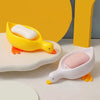 A yellow duck-shaped soap dish with a white bar of soap is displayed on a white surface.