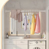 A bathroom interior showing a white vanity, mirror, and a stainless steel shower curtain rod with various fabric curtains.