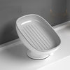 A white ceramic countertop soap dish with a slatted drainage area and a suction cup base.