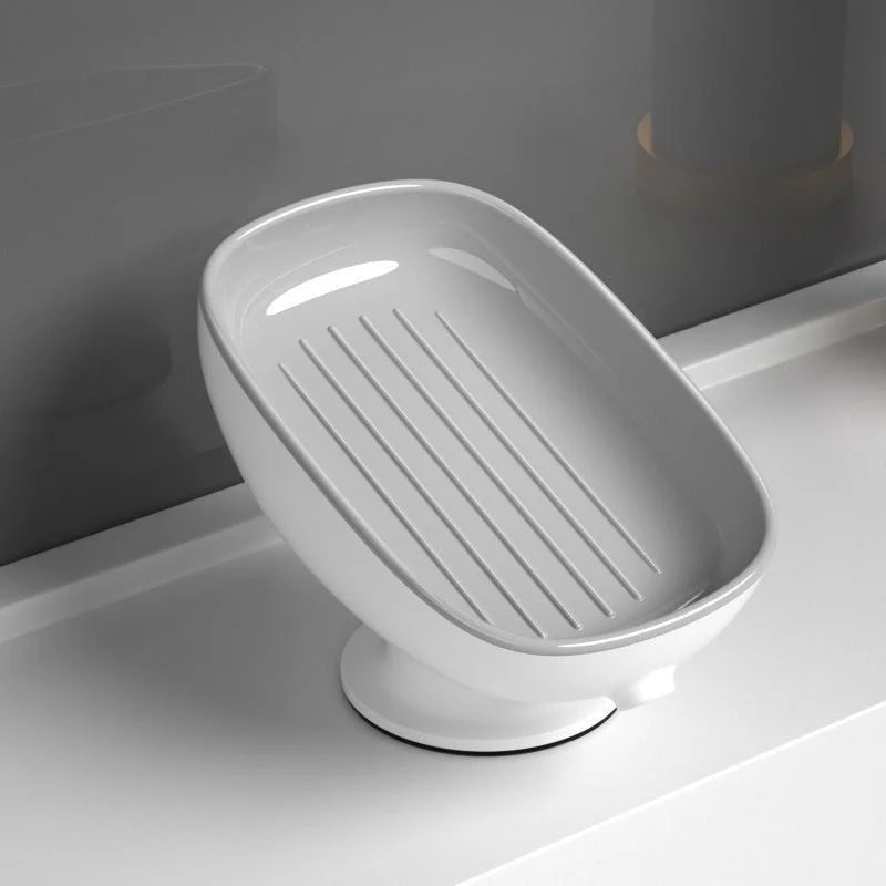 A white ceramic countertop soap dish with a slatted drainage area and a suction cup base.