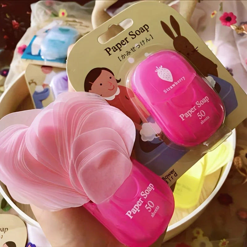 Paños de jabón de papel rosa en un paquete transparente con diseño de fresa y una mano rosa apretando una lámina.