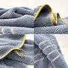 Close-up view of a soft gray microfiber bath towel with gold trim and looped texture.