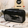 A black transparent pencil pouch is displayed on a white surface next to various writing tools and accessories.