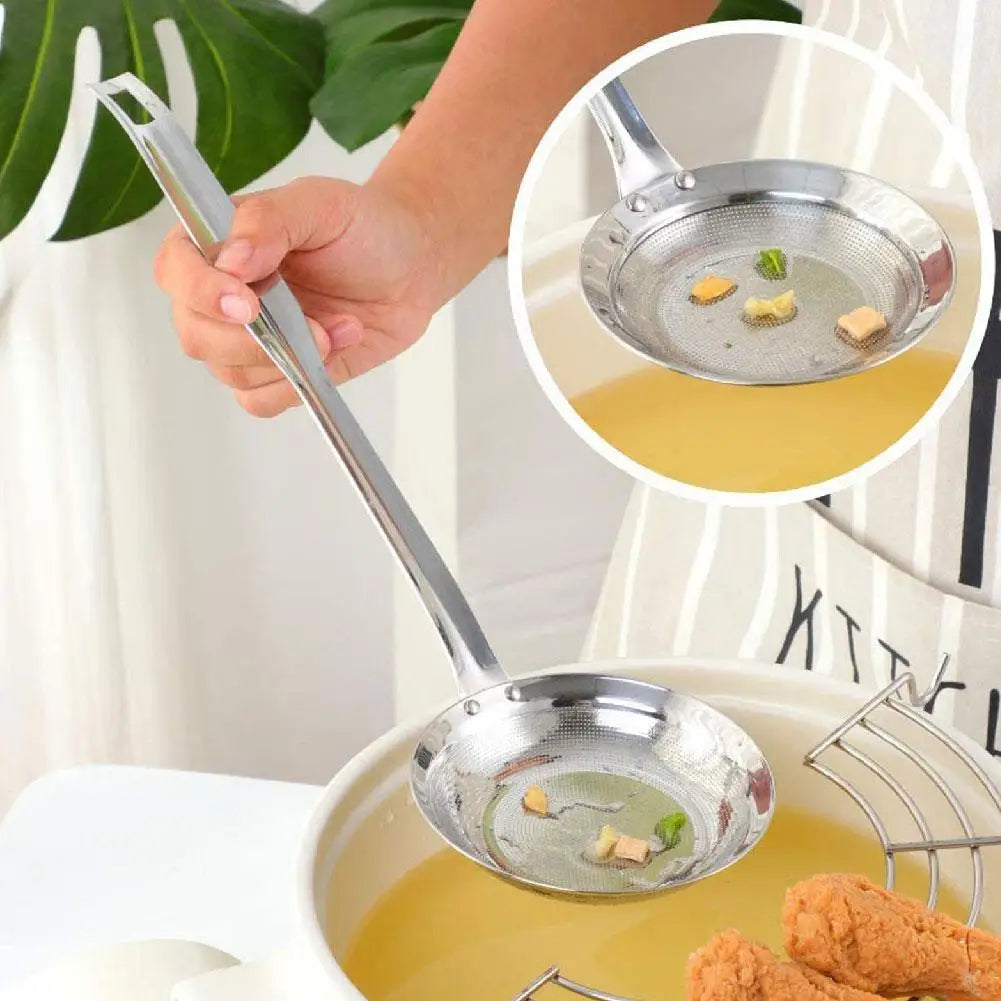 A hand is using a stainless steel fat skimmer strainer to remove fat from soup in a pot.