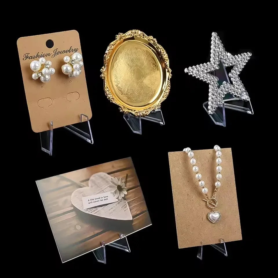 Three clear acrylic display stands showcasing gold and silver jewelry pieces.