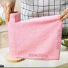 A hand holds a pink reusable microfiber cleaning cloth, measuring 20cm/7.87in, against a checkered background.
