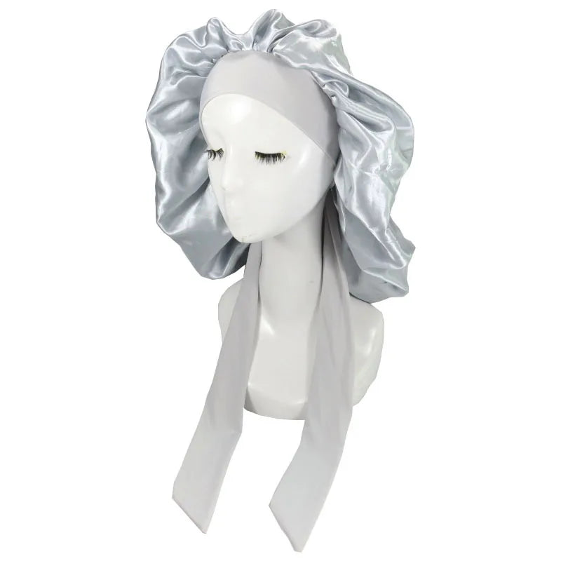 A white mannequin head wearing a silver satin sleep bonnet and hair cap.