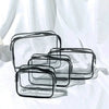 A set of three clear and black transparent travel makeup organizer bags lying on a white surface.