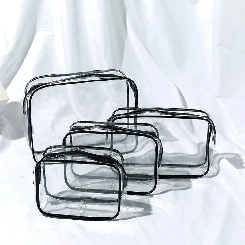 A set of three clear and black transparent travel makeup organizer bags lying on a white surface.