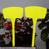 Two bright yellow T-shaped plant markers standing in a potted plant display.