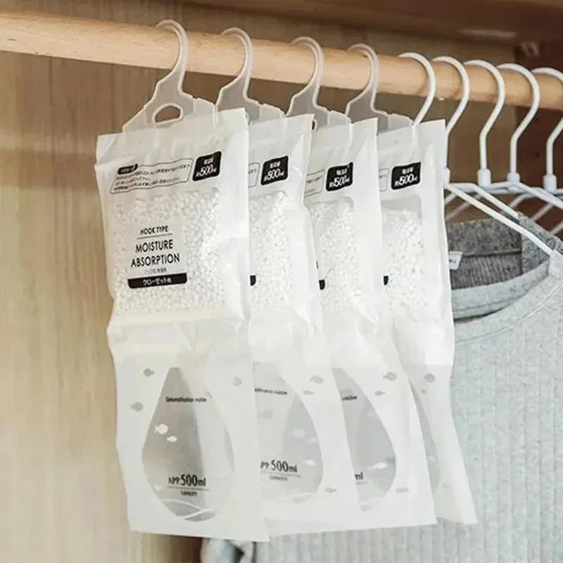 Un paquet de sachets absorbants d'humidité blancs suspendus sur un porte en bois.