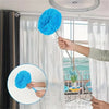 A hand is using an extendable microfiber duster to clean a window with sheer curtains.