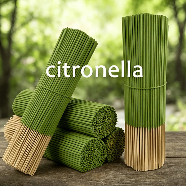 Green citronella oil sticks standing upright on a wooden surface with fresh greenery in the background.