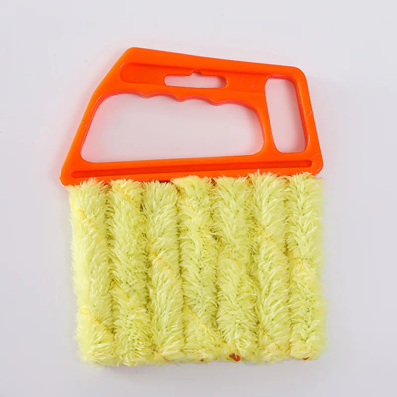 An orange detachable window blind cleaning brush with a yellow bristled head.