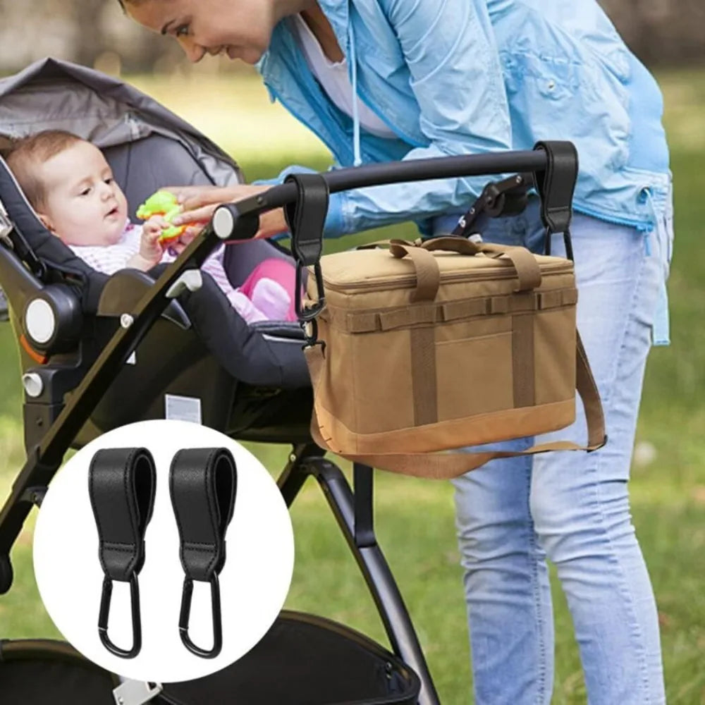 A woman is using a stroller hook carabiner accessory to attach a canvas bag to a stroller.