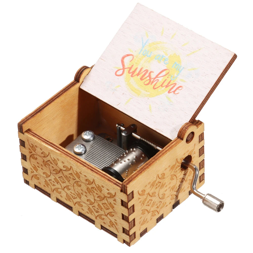 A vintage engraved wooden music box with a lid featuring the text You are my sunshine.